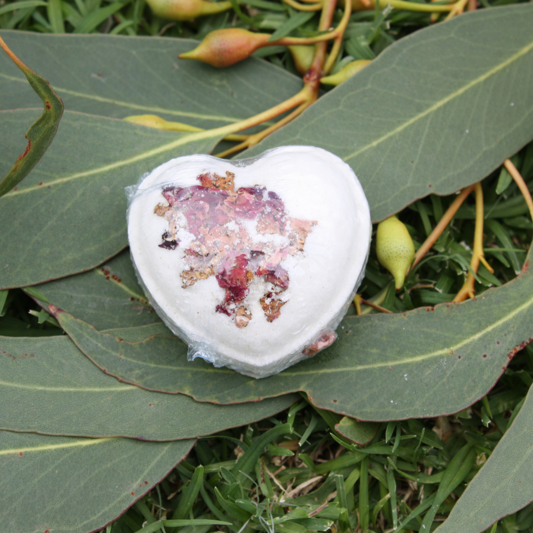 Heart-shaped bath bomb with decorative elements on green leaves