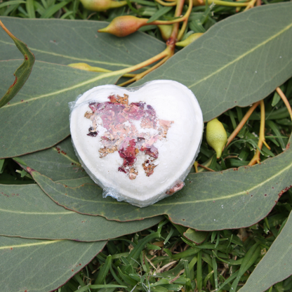 Heart-shaped bath bomb with decorative elements on green leaves